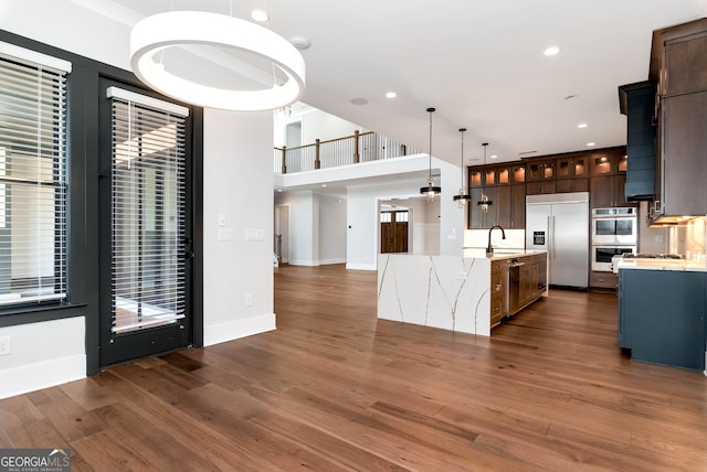 kitchen with glass insert cabinets, appliances with stainless steel finishes, dark wood-style floors, and pendant lighting