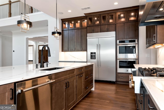 kitchen featuring stainless steel appliances, wall chimney range hood, visible vents, a sink, and dark wood-type flooring