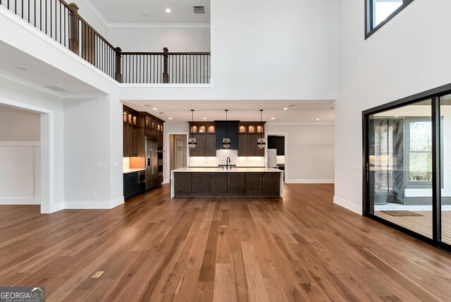 living area featuring visible vents, baseboards, ornamental molding, recessed lighting, and wood finished floors