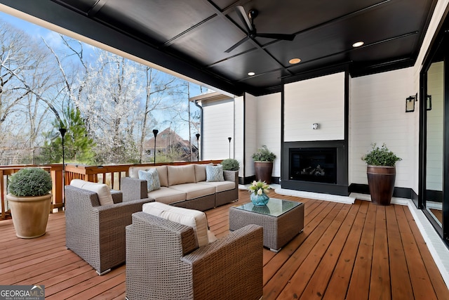deck with an outdoor living space with a fireplace