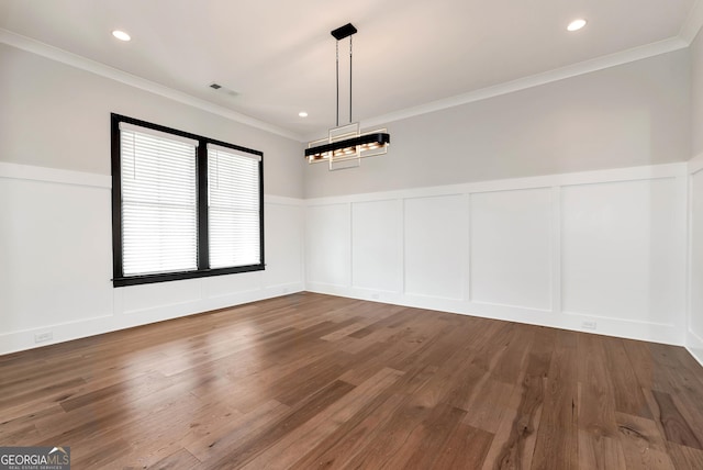 unfurnished dining area featuring crown molding, wood finished floors, visible vents, and a decorative wall