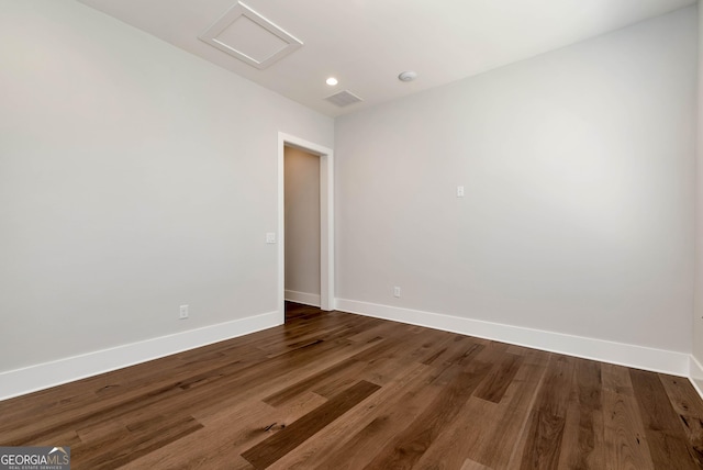 empty room with attic access, wood finished floors, baseboards, and visible vents