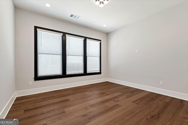 unfurnished room with baseboards, dark wood-type flooring, and visible vents
