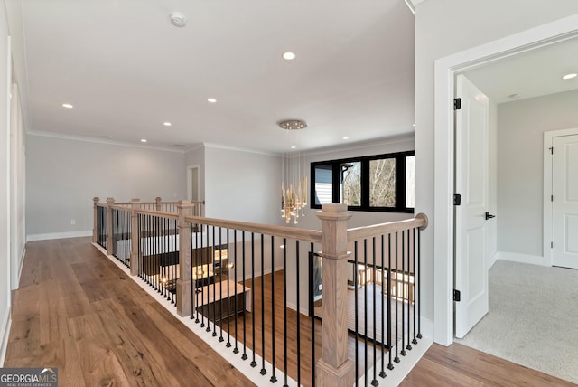 hall with an upstairs landing, ornamental molding, wood finished floors, recessed lighting, and baseboards