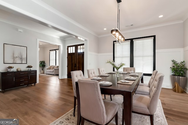 dining space with visible vents, wainscoting, light wood-style floors, and ornamental molding