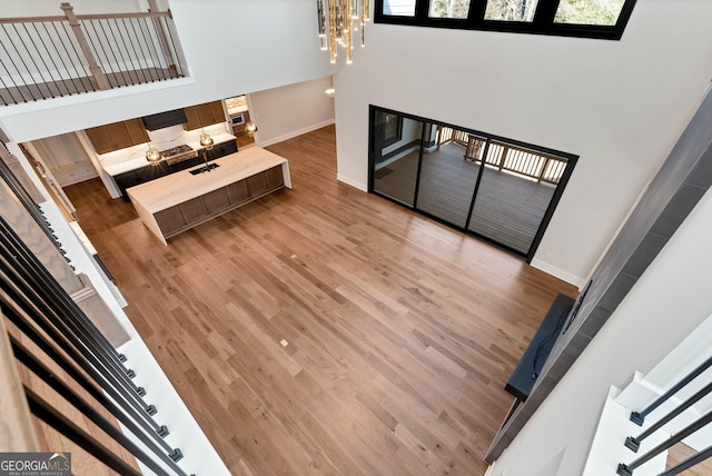 living area featuring wood finished floors, a high ceiling, baseboards, a chandelier, and stairs