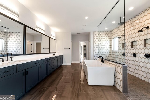 full bathroom featuring double vanity, a freestanding tub, recessed lighting, a sink, and a walk in shower