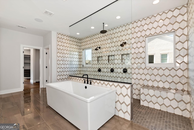 full bath with visible vents, tile walls, walk in shower, and a freestanding tub