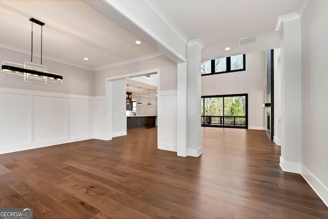 interior space featuring a decorative wall, dark wood-style floors, visible vents, and ornamental molding