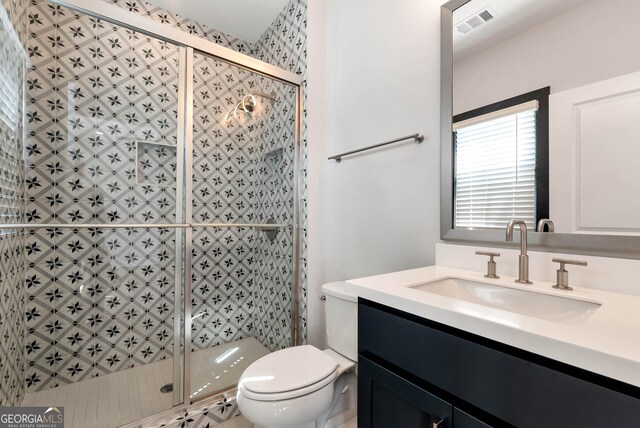 bathroom with visible vents, a shower stall, toilet, and vanity