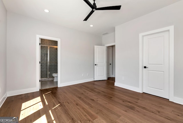 unfurnished bedroom with wood finished floors, visible vents, baseboards, and ensuite bathroom