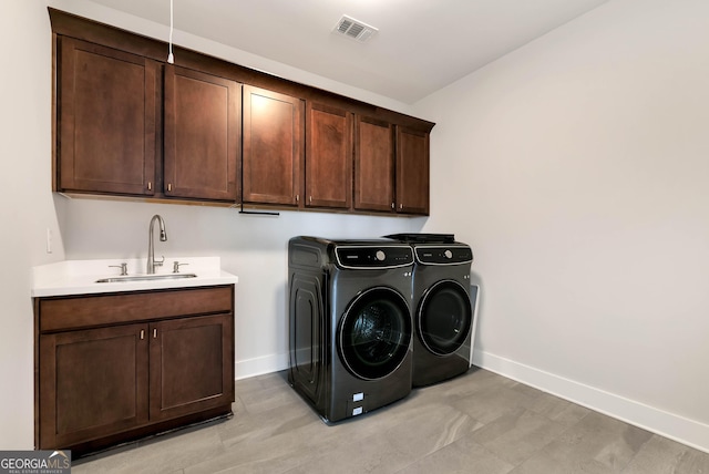 washroom with a sink, visible vents, baseboards, cabinet space, and washer and dryer