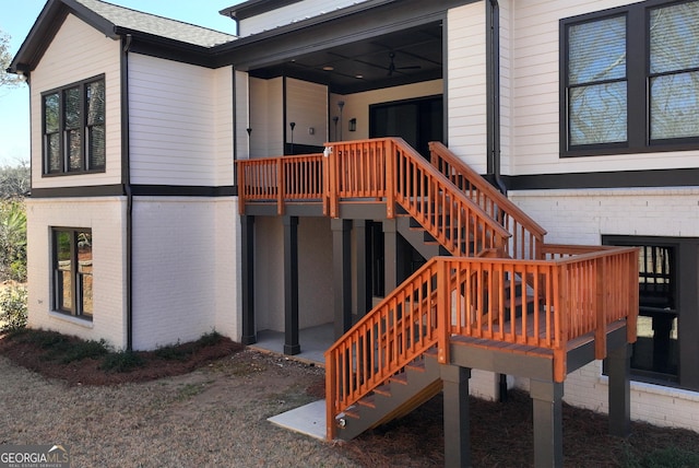 entrance to property with brick siding, a deck, and a shingled roof