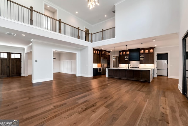 unfurnished living room featuring visible vents, baseboards, dark wood finished floors, a chandelier, and ornamental molding