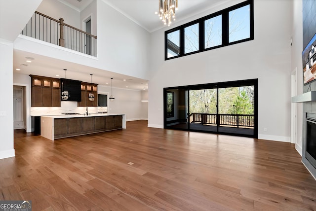 unfurnished living room featuring baseboards, wood finished floors, a high ceiling, and a fireplace