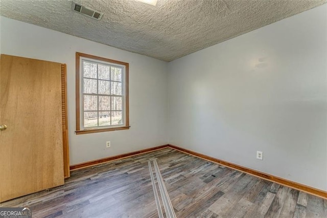 unfurnished room with visible vents, baseboards, and wood finished floors