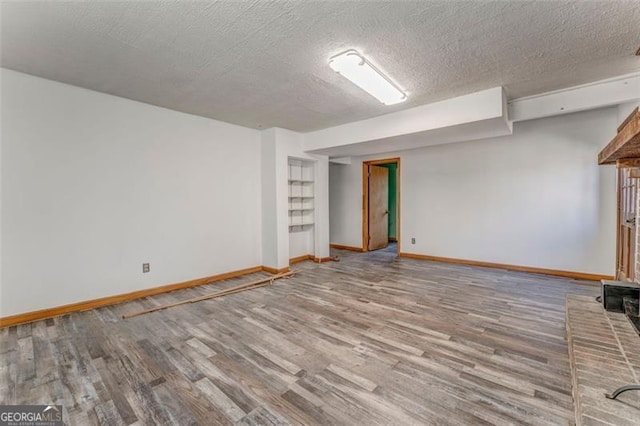 below grade area featuring a textured ceiling, baseboards, and wood finished floors