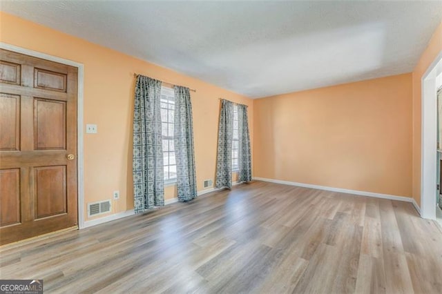 interior space with light wood finished floors, visible vents, and baseboards