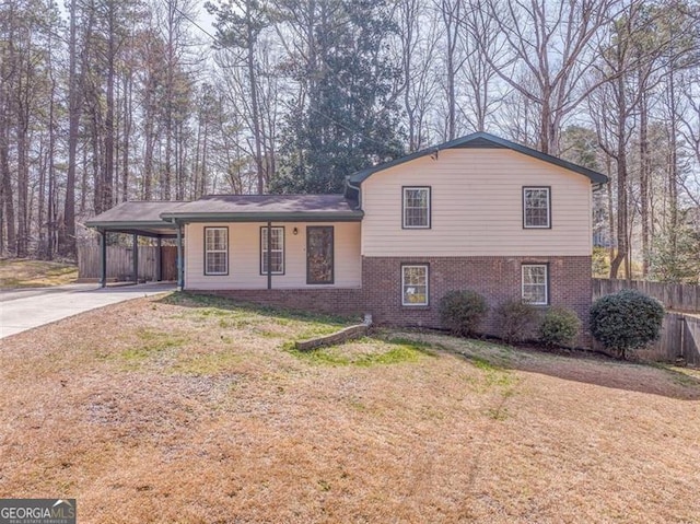 split level home with brick siding, fence, concrete driveway, a front yard, and a carport