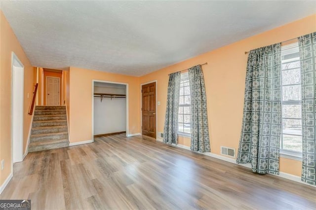 unfurnished bedroom with wood finished floors, baseboards, visible vents, a closet, and a textured ceiling