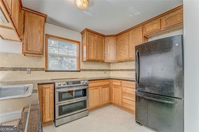 kitchen with backsplash, double oven range, freestanding refrigerator, and a sink