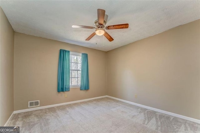 spare room featuring visible vents, baseboards, a textured ceiling, and carpet flooring