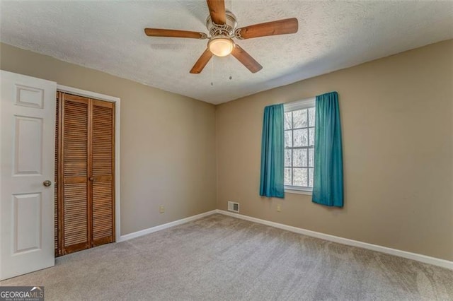 unfurnished bedroom featuring baseboards, a closet, carpet floors, and a textured ceiling