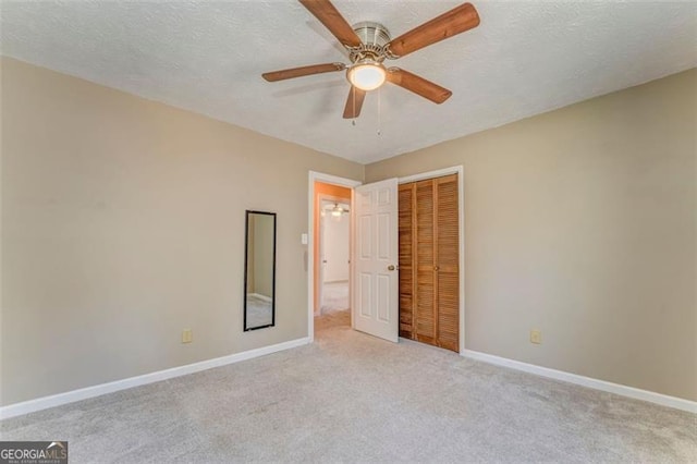 unfurnished bedroom featuring baseboards, ceiling fan, a closet, a textured ceiling, and carpet flooring