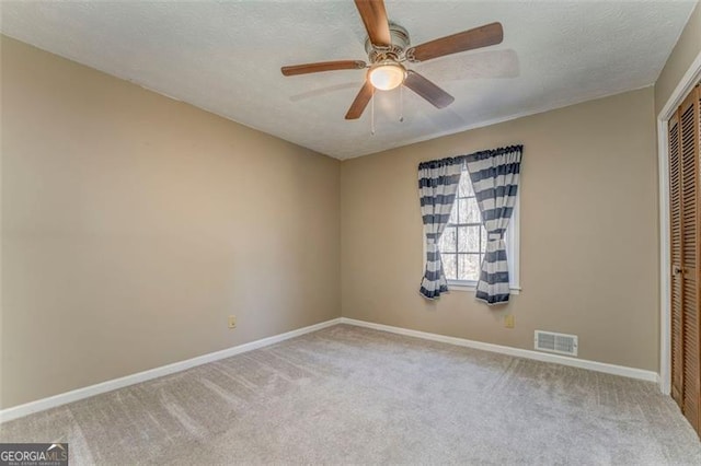 carpeted spare room with a ceiling fan, baseboards, visible vents, and a textured ceiling