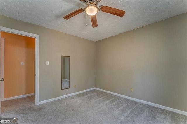 carpeted empty room with a textured ceiling, baseboards, and a ceiling fan