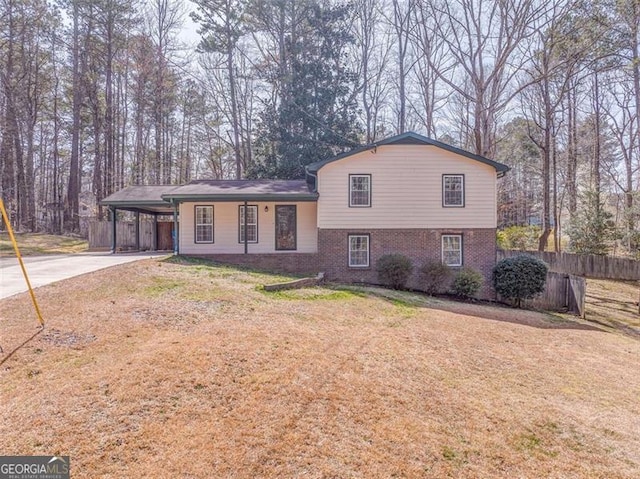 tri-level home featuring fence, a carport, concrete driveway, a front lawn, and brick siding