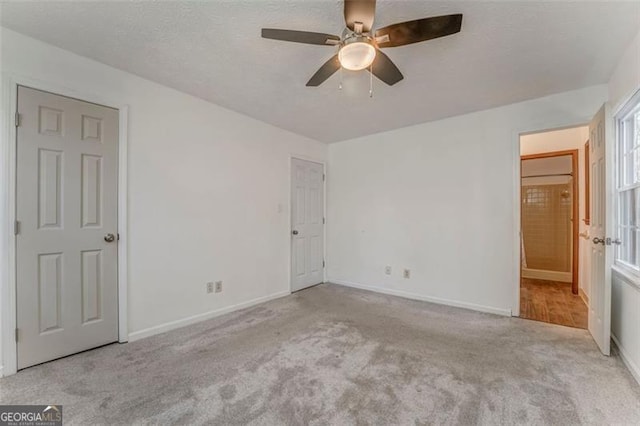 unfurnished bedroom with ceiling fan, carpet flooring, baseboards, and a textured ceiling