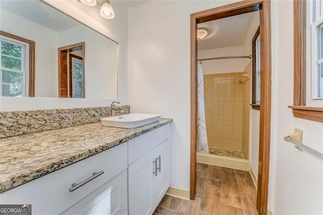 bathroom with a stall shower, vanity, baseboards, and wood finished floors