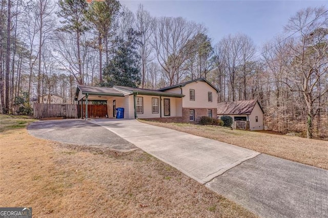 tri-level home with brick siding, concrete driveway, a front lawn, and fence