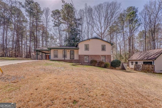 tri-level home with an attached carport, brick siding, driveway, and a front lawn