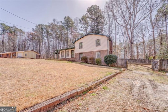 view of front of property featuring brick siding, an outdoor structure, a front yard, and fence