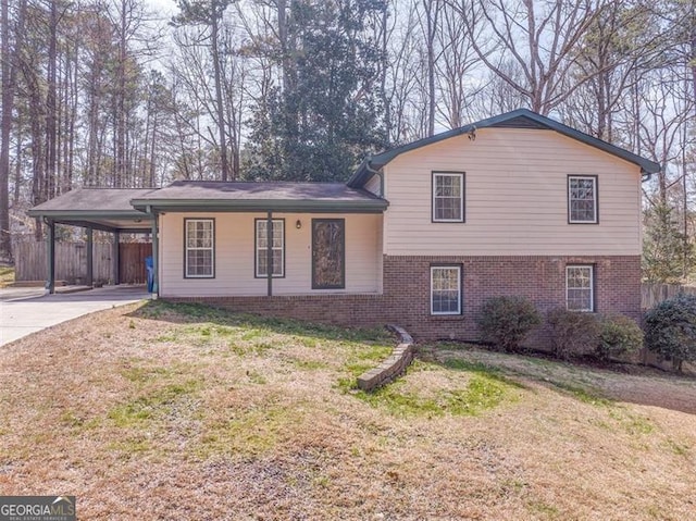 tri-level home with a front lawn, a carport, brick siding, and fence