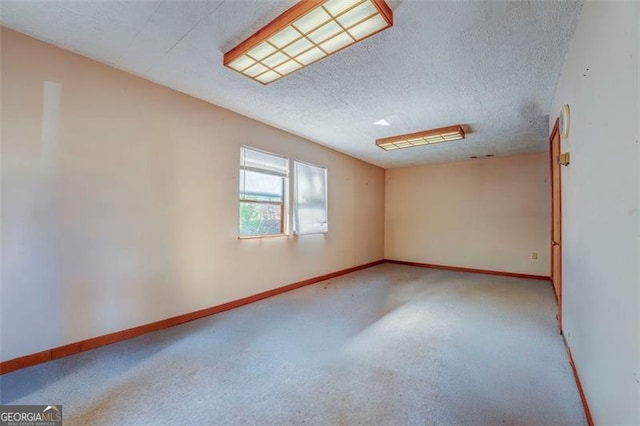 carpeted empty room with baseboards and a textured ceiling