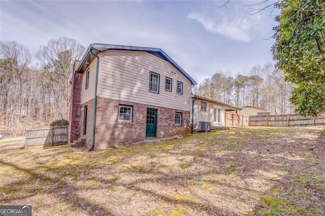 back of house featuring brick siding, central air condition unit, and fence