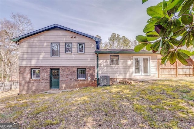 rear view of house with brick siding, french doors, fence, and central AC