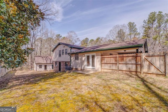 rear view of property featuring a yard, fence, and french doors