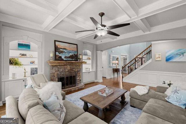 living area with built in shelves, wood finished floors, a ceiling fan, coffered ceiling, and beam ceiling