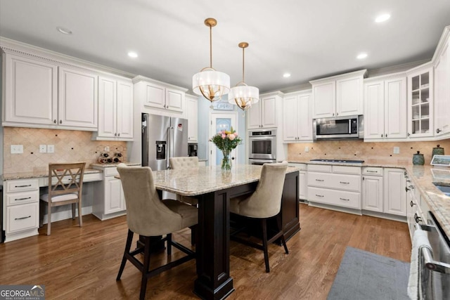 kitchen featuring white cabinets, appliances with stainless steel finishes, a breakfast bar, and an inviting chandelier