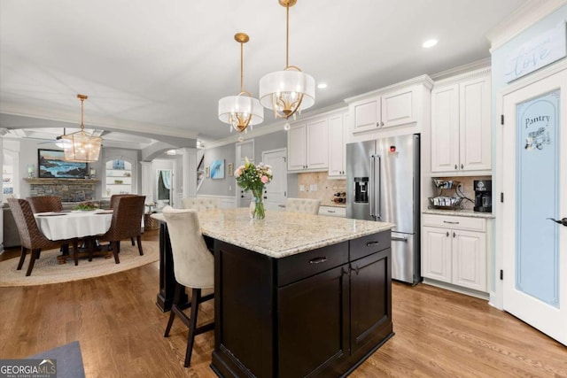 kitchen with arched walkways, pendant lighting, white cabinetry, and high quality fridge