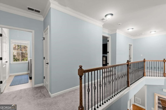 corridor with visible vents, an upstairs landing, carpet flooring, and crown molding