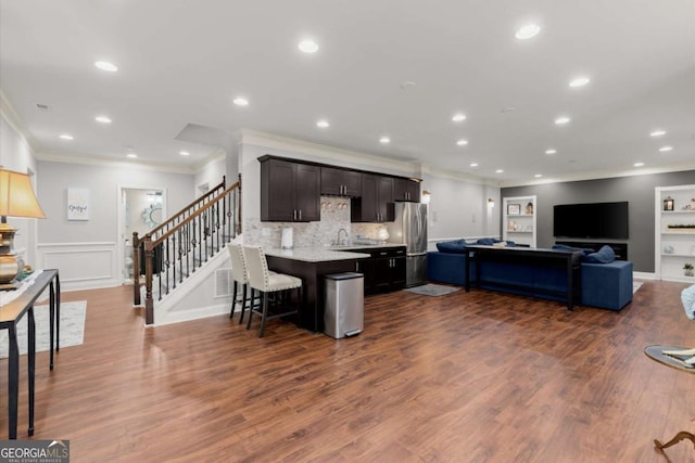 kitchen featuring open floor plan, freestanding refrigerator, recessed lighting, a breakfast bar area, and dark wood-style flooring