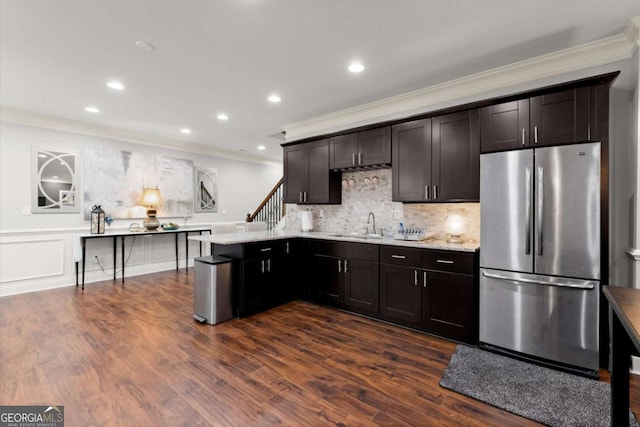 kitchen featuring dark wood finished floors, ornamental molding, a peninsula, freestanding refrigerator, and a sink