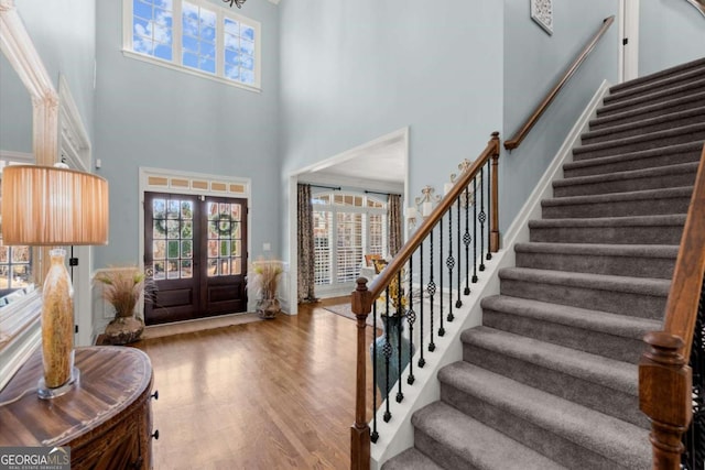 foyer with stairway, a healthy amount of sunlight, french doors, and wood finished floors