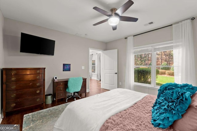 bedroom with ceiling fan, visible vents, and wood finished floors