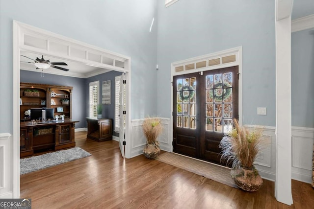 foyer featuring wainscoting, french doors, crown molding, and wood finished floors